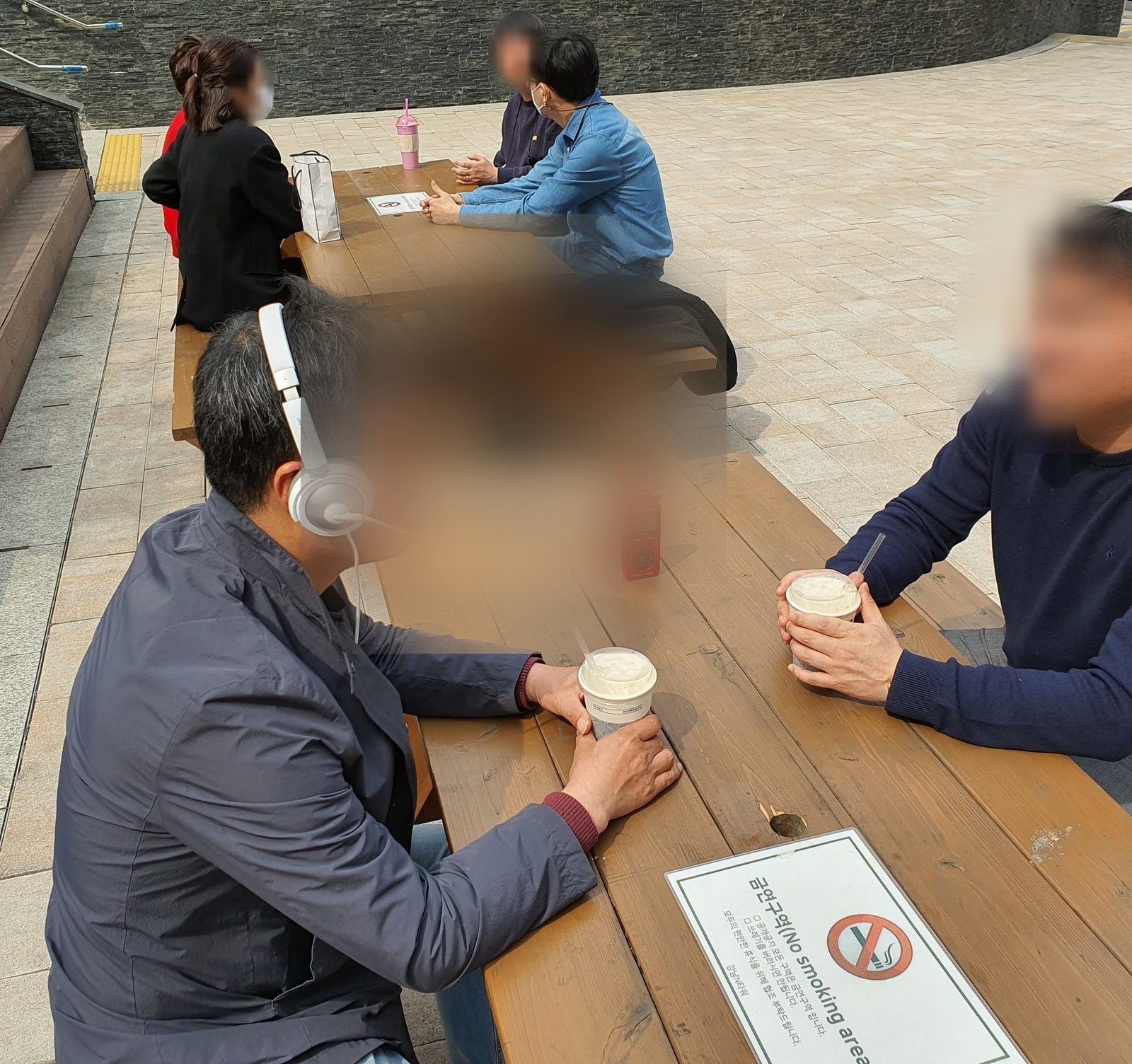 야외 테이블에서 헤드셋을 착용하고 대화를 녹음하는 참여자들
